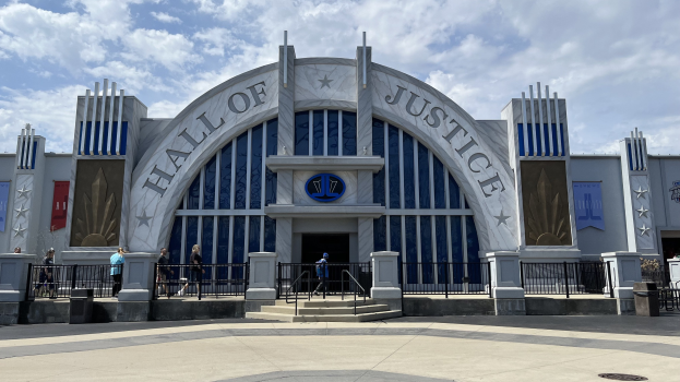 Der Eingang zum Hall of Justice im Disney's Hollywood Studios, mit einer Gruppe von Menschen davor, unter einem bewölkten Himmel.