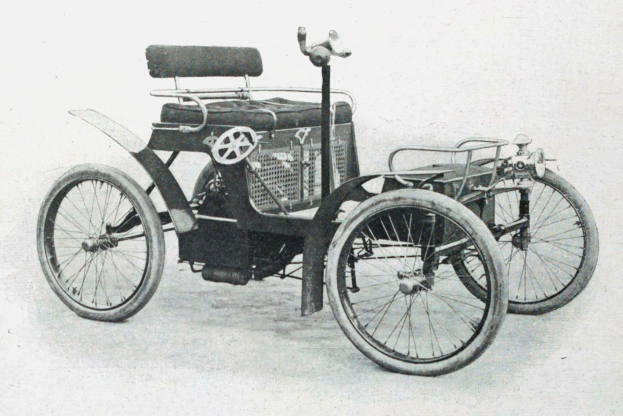 Vintage-Schwarz-Weiß-Foto eines frühen 1900er-Elektroautos mit schlankem, aerodynamischem Design, großem runden Scheinwerfer, geschwungener Dachlinie, vier großen Rädern, einem prominenten Heckmotor, leichtem Polsterbezug und einem Armaturenbrett mit Knöpfen und Drehreglern.