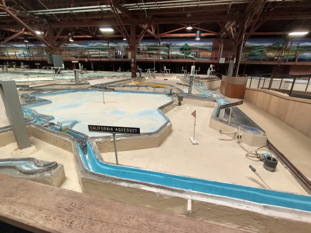Indoor-Wasserpark mit mehreren Wasserrutschen, Deckenbeleuchtung, Wandgemälden und einem Minigolfbereich.
