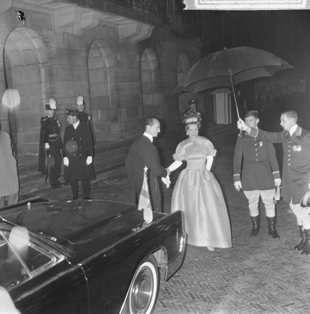Schwarzes und weißes Foto von Queen Elizabeth II und Prince Philip bei der Ankunft im Buckingham Palace, Queen hält einen Blumenstrauß, Philip hält einen Schirm, gekleidet in formeller Kleidung.