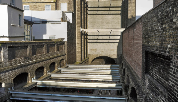 Gebäude mit einem durch einen Tunnel fahrenden Zug im Hintergrund.