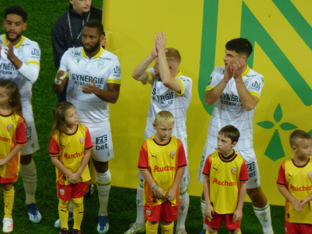Eine Gruppe von Fussballspielern in Uniformen klatscht auf einem Ligue 1 Feld in celebration