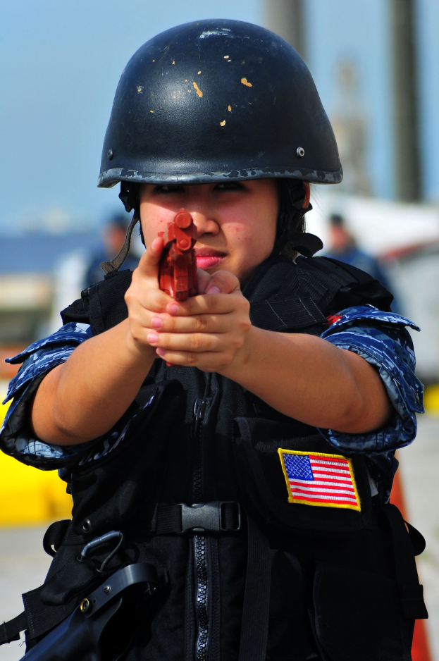 Ein Polizist in Uniform hält eine Waffe, mit Helm, mit einem unscharfen Hintergrund.