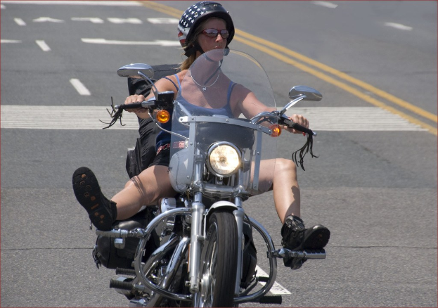 Eine Frau fährt mit einem Fahrrad auf einer Straße und trägt einen schwarzen Helm.