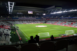 Großes Stadion voller Zuschauer bei einem Fußballspiel im Estadio Santiago Bernabeu in Madrid, Spanien, mit sitzenden und stehenden Zuschauern unter Stadionbeleuchtung und einem großen Bildschirm oben.