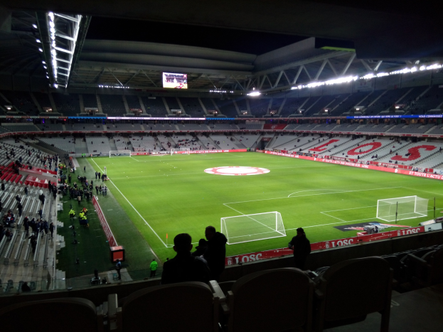 Großes Stadion voller Zuschauer bei einem Fußballspiel im Estadio Santiago Bernabeu in Madrid, Spanien, mit sitzenden und stehenden Zuschauern unter Stadionbeleuchtung und einem großen Bildschirm oben.