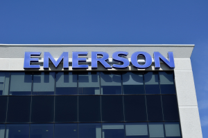 Emerson-Logo auf einem Gebäude mit dem Text "Emerson investiert $1,5 Milliarden in den USA" vor einem klaren blauen Himmel.