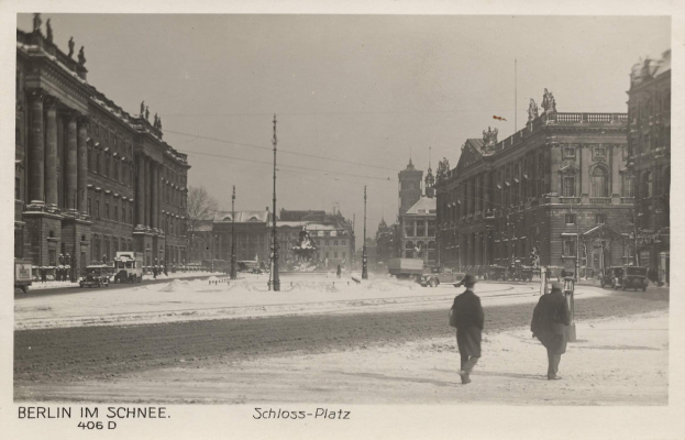 Zwei Menschen spazieren auf einer verschneiten Straße in Berlin, Deutschland, mit Gebäuden, Pfählen und Fahrzeugen, die die Straße säumen und der Himmel im Hintergrund sichtbar ist.