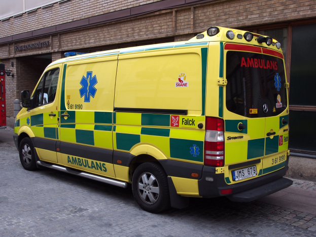 Ambulanz auf der Straße vor einem Backsteingebäude mit Text geparkt, mit einem Feuerlöscher auf der linken Seite zu sehen.
