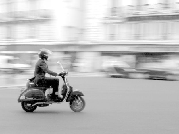 Eine Person fährt mit einem Roller auf der Straße.