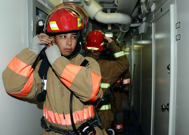 Feuerwehrleute in Uniform, die in einem Raum mit Rohren und Geräten während eines Trainingsübung stehen.