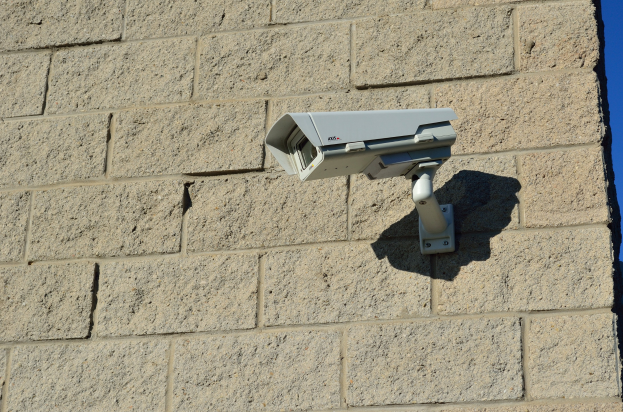 Sicherheitskamera an der Seite eines Gebäudes unter einem hellblauen Himmel.