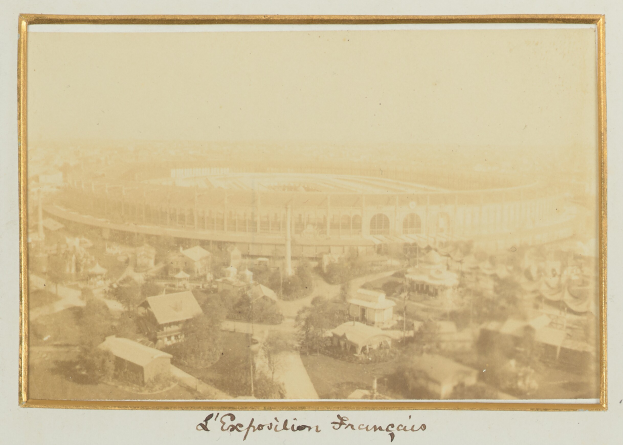 Altes Schwarz-Weiß-Foto eines Stadions umgeben von städtischen Gebäuden, Bäumen und Strommasten mit Text unten.