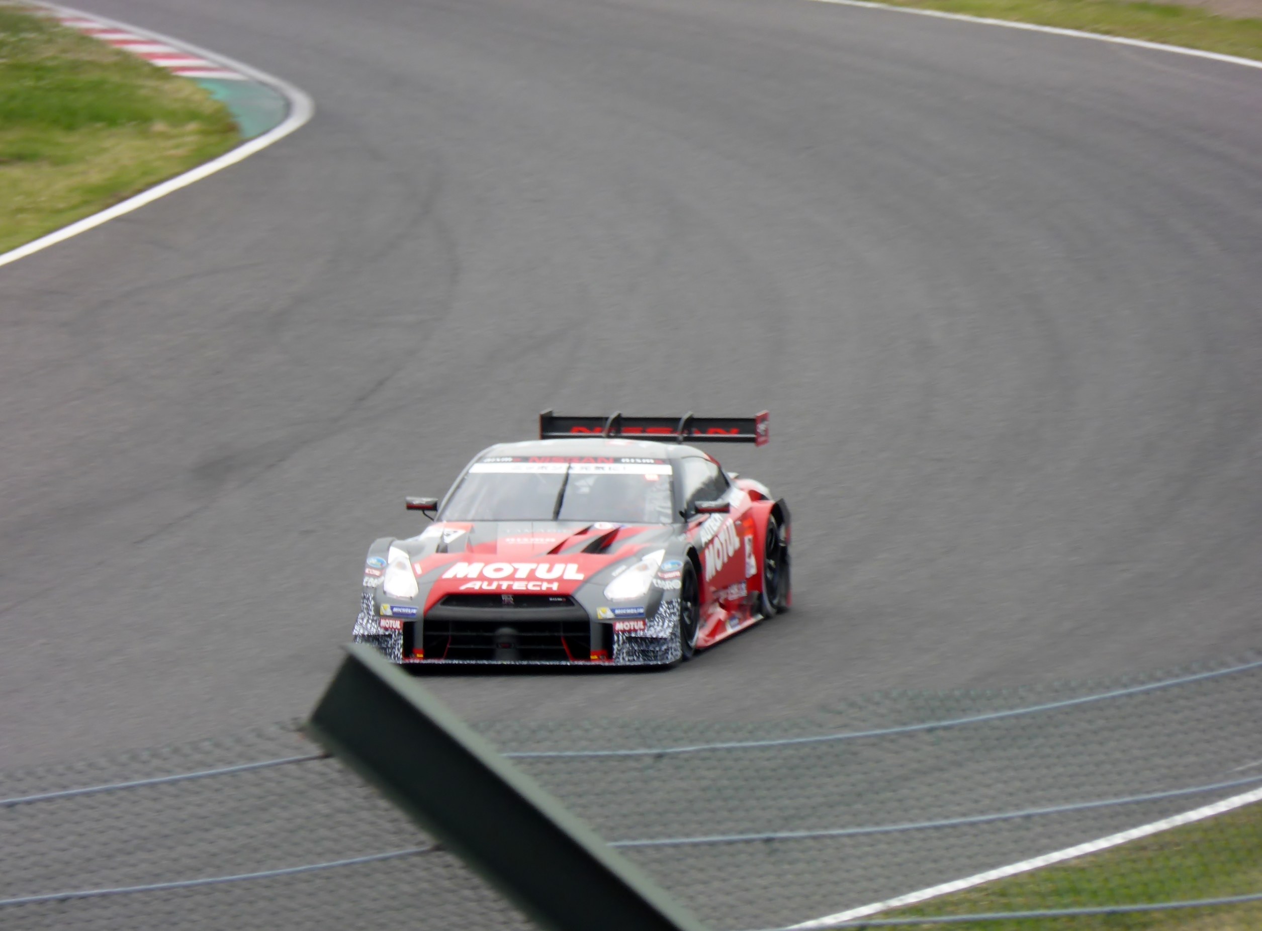 Ein Nissan GT-R Nismo GT3 Rennauto auf der Nürburgring 24 Stunden Rennstrecke, mit grünem Gras auf beiden Seiten der Strecke.