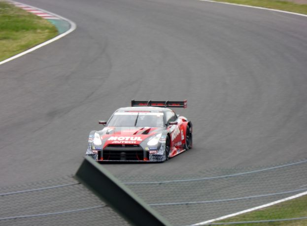Ein Nissan GT-R Nismo GT3 Rennauto auf der Nürburgring 24 Stunden Rennstrecke, mit grünem Gras auf beiden Seiten der Strecke.
