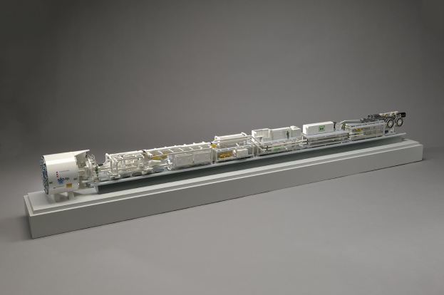 Ausf%C3%BChrliches Modell eines Sainsbury's Wasserstoff-Brennstoffzellensystems auf einer wei%C3%9Fen Oberfl%C3%A4che, das Komponenten wie einen Kraftstofftank, Filter und Einspritzventil zeigt, die mit einer Stromquelle verbunden sind.