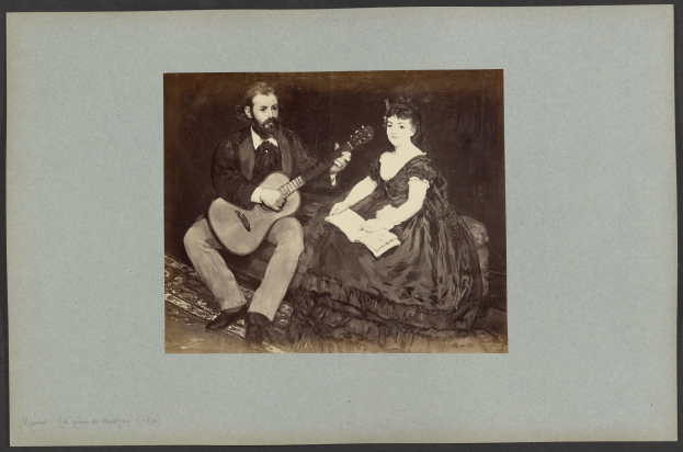 Ein Mann im Anzug und eine Frau, beide halten Gitarren und Papierstücke in den Händen und sitzen friedlich nebeneinander.