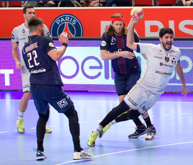 M├Ąnner spielen Hallenhandball auf einem Court mit einem Ball im Spiel, Zuschauer sitzen im Hintergrund und eine Tafel mit der Aufschrift "Futsal-Weltmeisterschaft 2019 - Paris Saint-Germain vs Marseille."