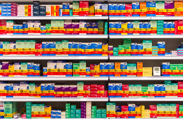 Ein Apothekeregal mit verschiedenen Medikamentenschachteln und Behältern, die ordentlich auf Gestellen angeordnet sind.