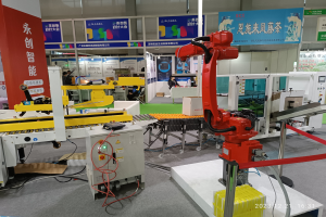 Gruppe von Robotern auf einem Tisch in einer Fabrikumgebung mit Maschinen, Leiterplatten, Drähten und Menschen im Hintergrund.