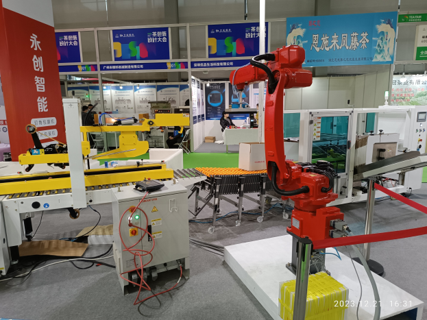 Gruppe von Robotern auf einem Tisch in einer Fabrikumgebung mit Maschinen, Leiterplatten, Drähten und Menschen im Hintergrund.