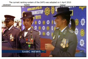 Gruppe von Menschen in Uniformen und Hüten mit einem Banner im Hintergrund, das Text an der Ober- und Unterseite trägt, der besagt "Das aktuelle Rankingsystem der SAP wurde am 1. April 2010 übernommen".