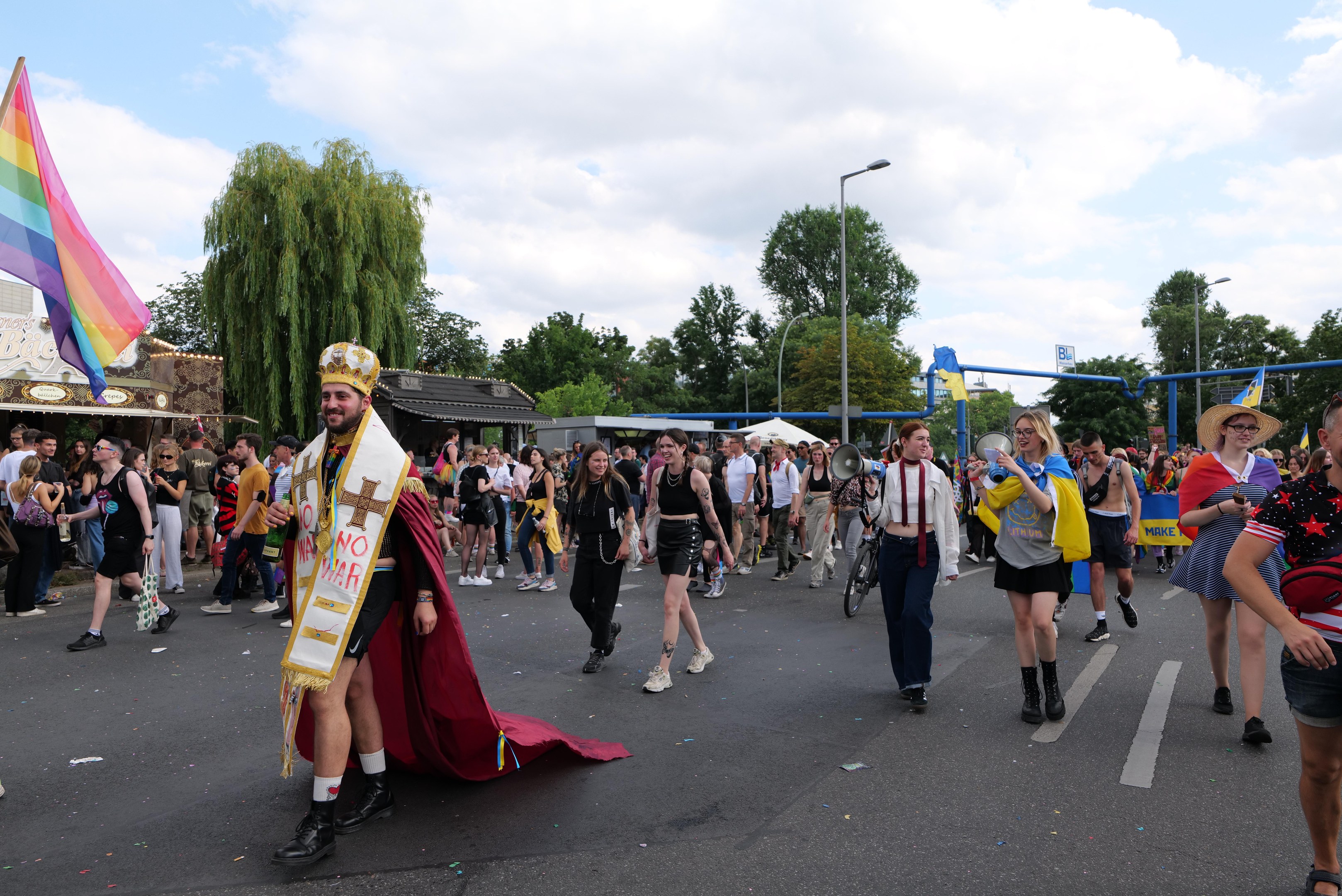 Eine Gruppe von Menschen, die bei der Pride Parade 2018 marschieren und eine Regenbogenflagge sowie Musikinstrumente tragen.