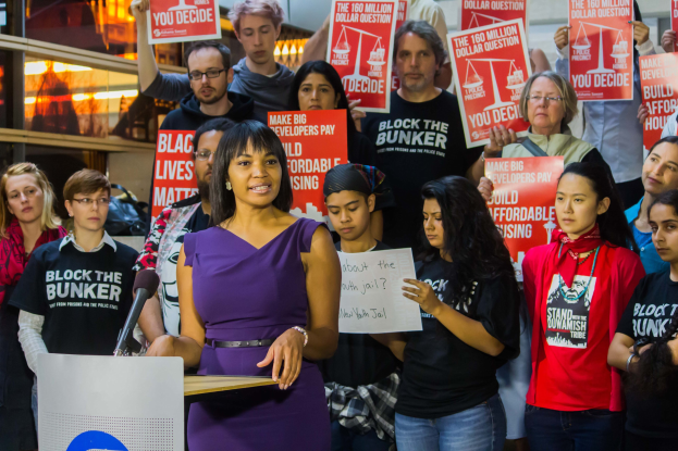 Aktivistin von Black Lives Matter spricht vor einem Publikum mit Mikrofon und Schildern.