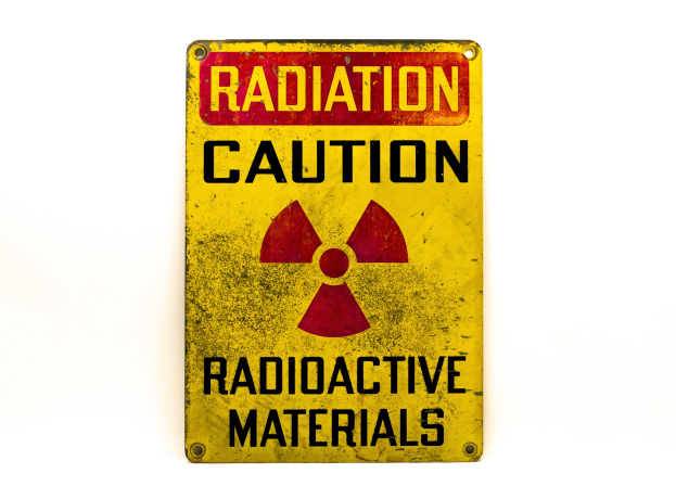 Gelbes Warnschild mit schwarzer "Strahlung Warnung"-Aufschrift und radioaktivem Symbol auf einem weißen Hintergrund.