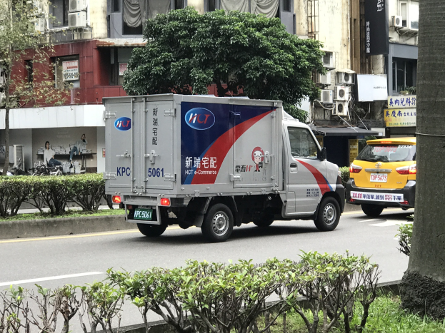 Ambulanz auf der Straßenseite neben einem Baum geparkt, mit Fahrzeugen, Gebäuden und anderen Objekten im Hintergrund.
